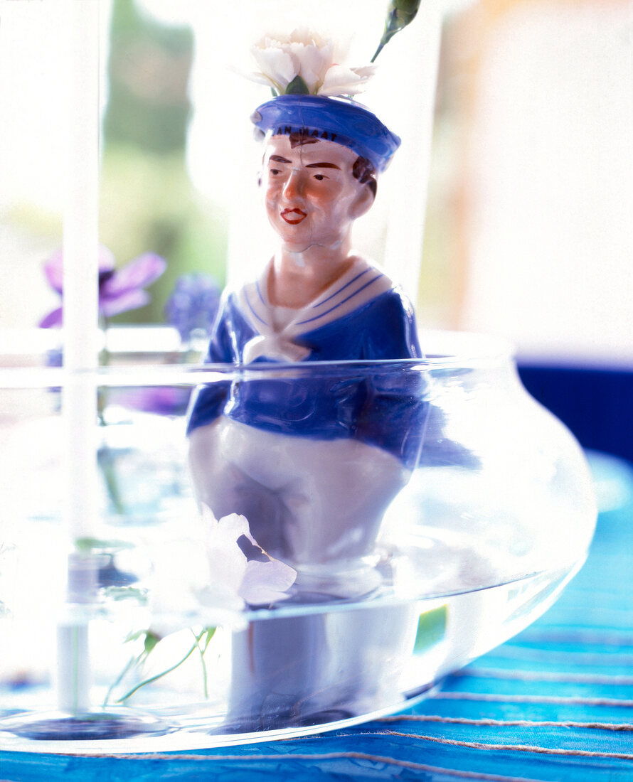 Close-up of porcelain man figurine in glass pot with water