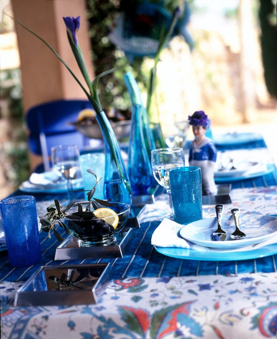 Table with blue table cloth, crockery, dishes and flower vase