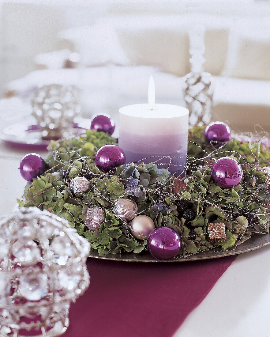 Purple layered lit candle decorated with hydrangea wreath and wire on plate