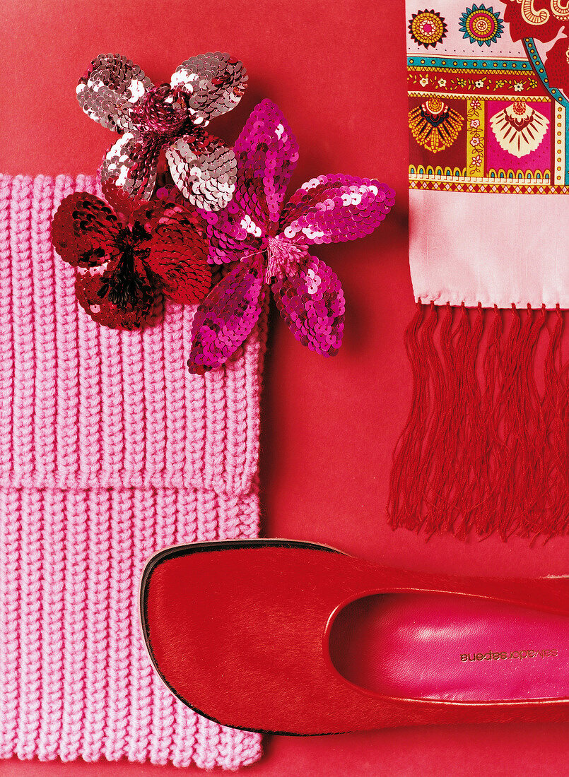 Brooches with sequins, embroidered fabric, red fur shoe and pink scarf on red background