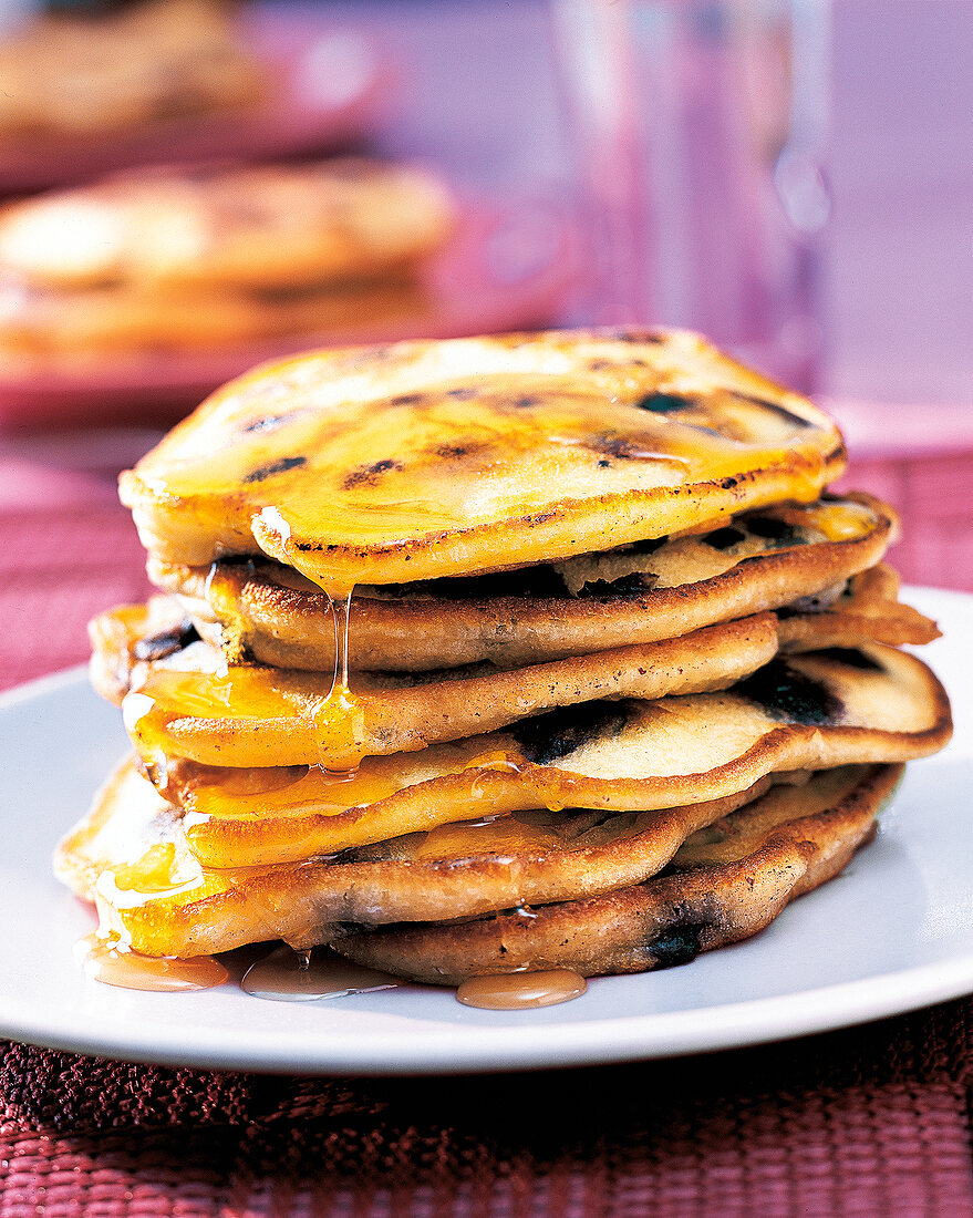 Stacks of blueberry pancakes with honey on plate