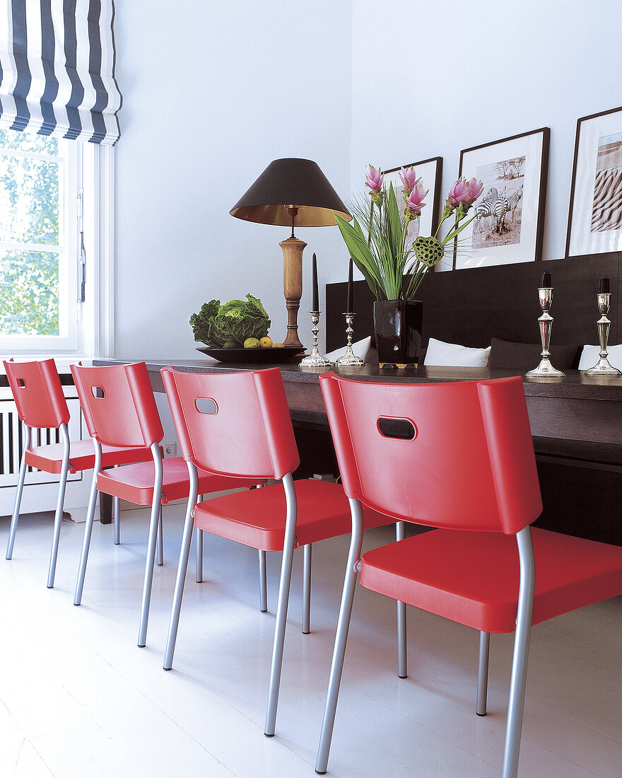 Stilmix: rote Kunststoffstühle vor elegantem dunklem Holtisch