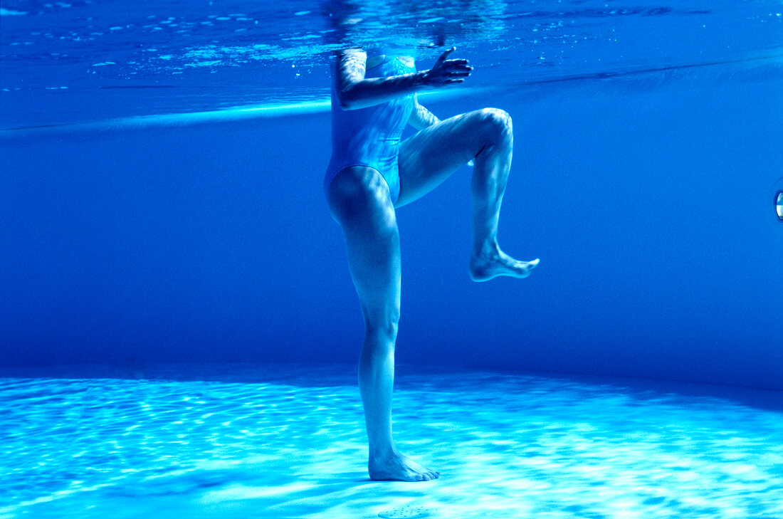 Woman cross-crawling in swimming pool for toning leg muscles