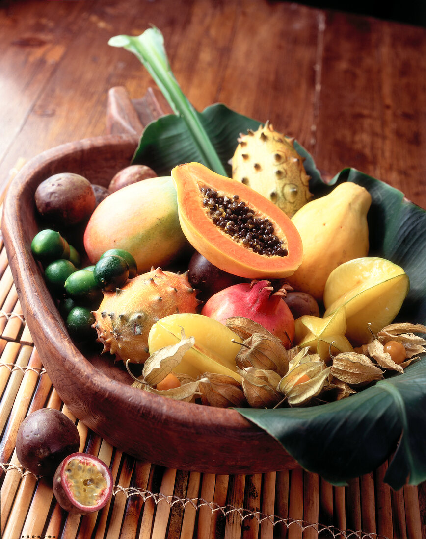 Horned melon, mango, papaya, physalis and Lime kept in wooden bowl