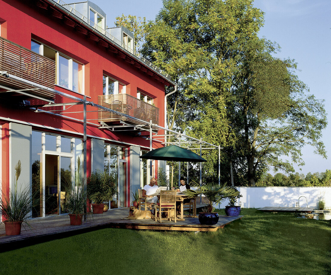 Terrasse vor Haus mit Roter Fassade, Aluminiumläden + Lärchenholzbalkons