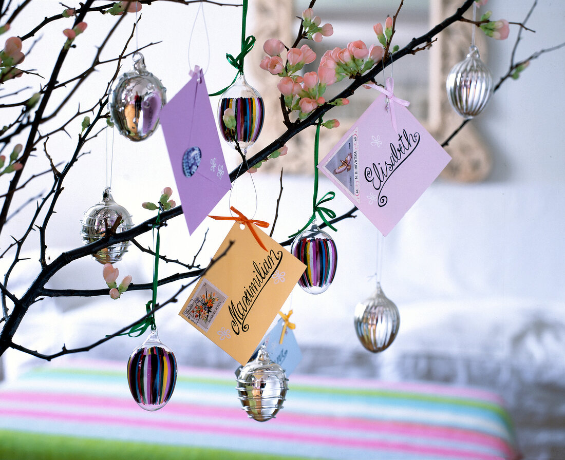 Mini letters and Easter eggs made of glass hanging on branches