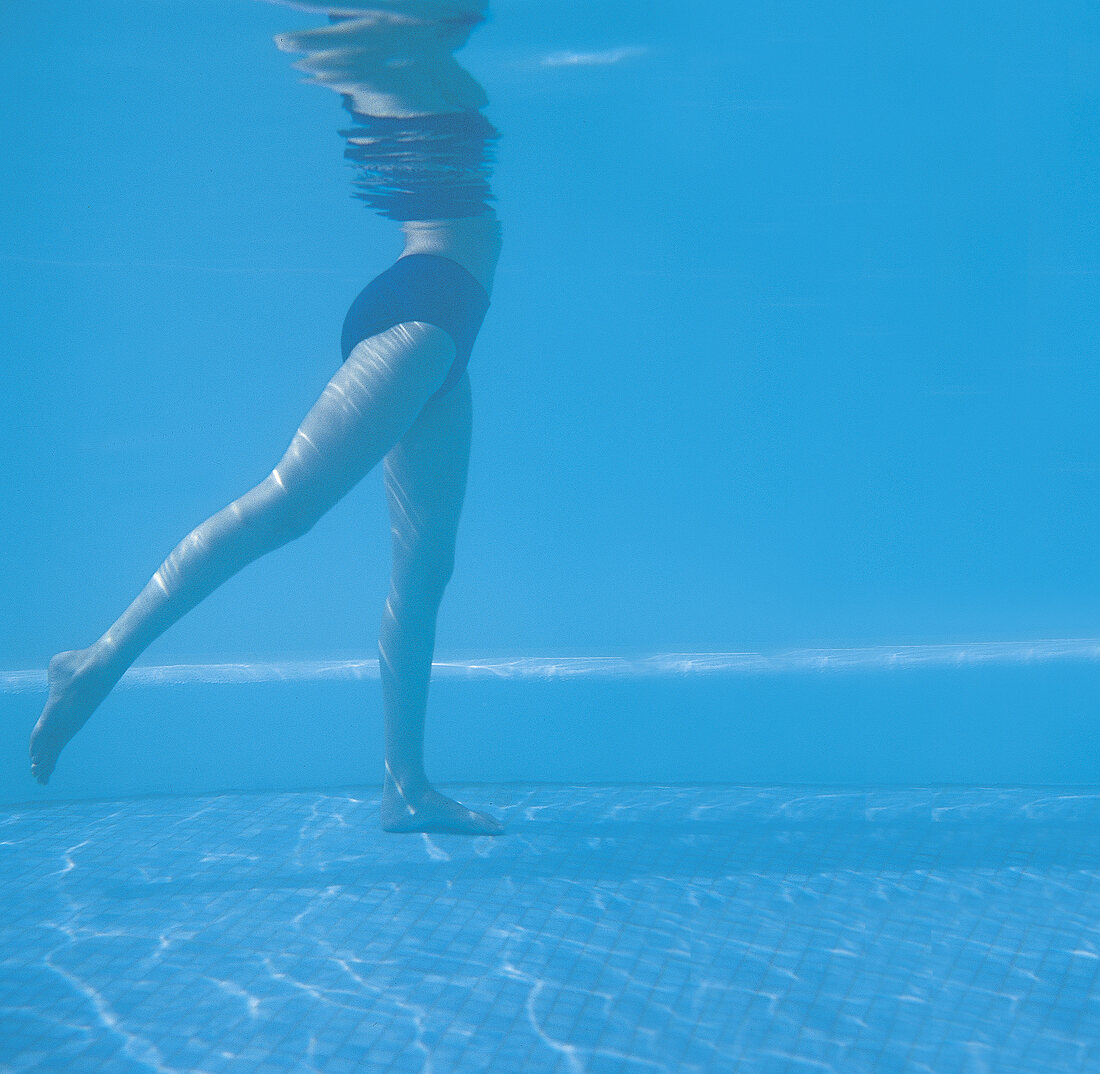 Frau im Pool bei Oberschenkelübung, Unterwasseraufnahme