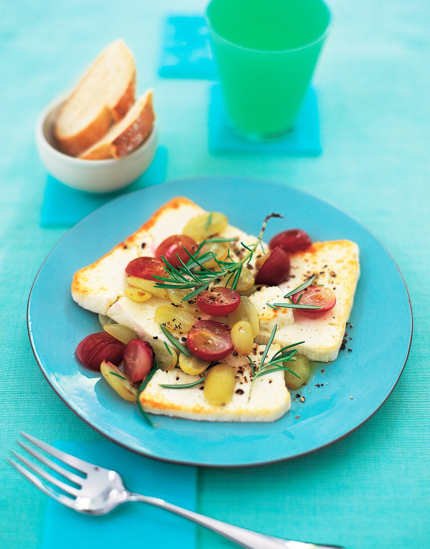 Feta gratin garnished with grapes and herbs on plate