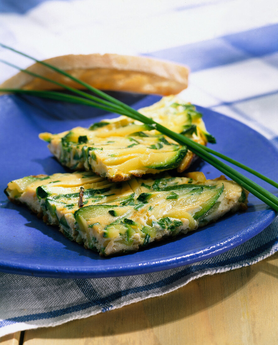 Zucchini frittata with vegetables and omelettes on blue plate