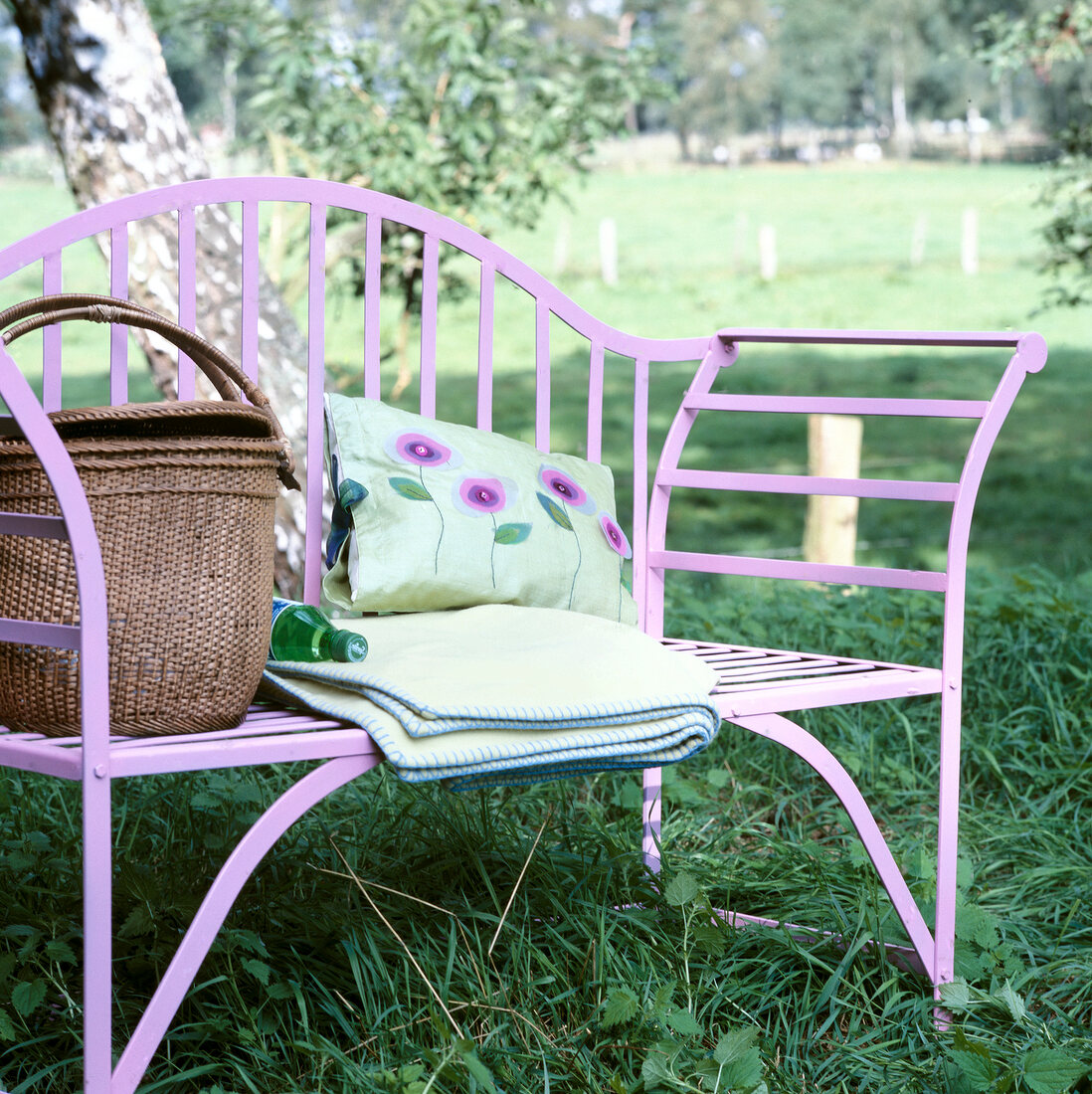 Purple garden chair with folded blanket, basket and pillow in garden