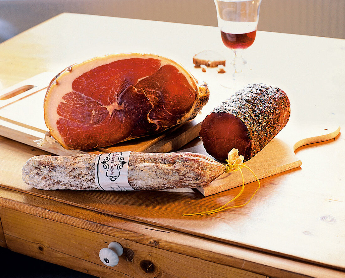 2 Schinken + eine Salami aus der Toskana, Glas Rotwein im Hintergrund