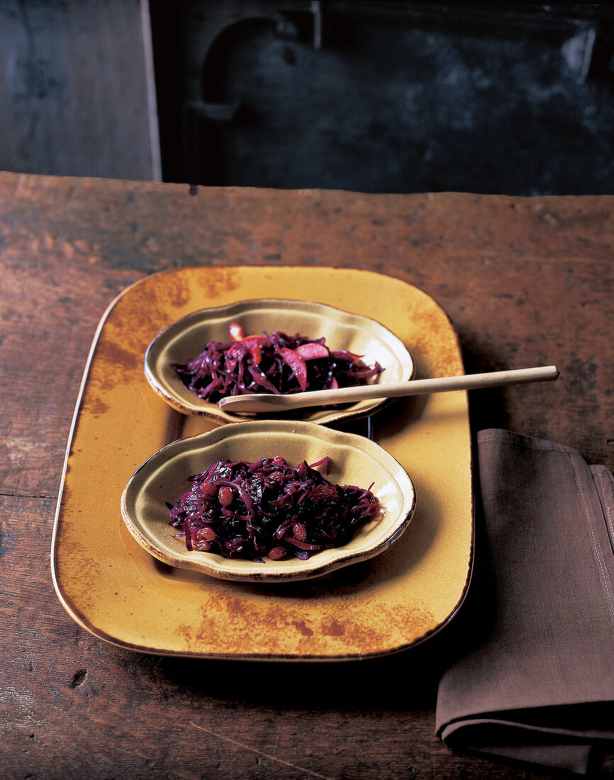 Red cabbage with apples with wooden spoon on tray