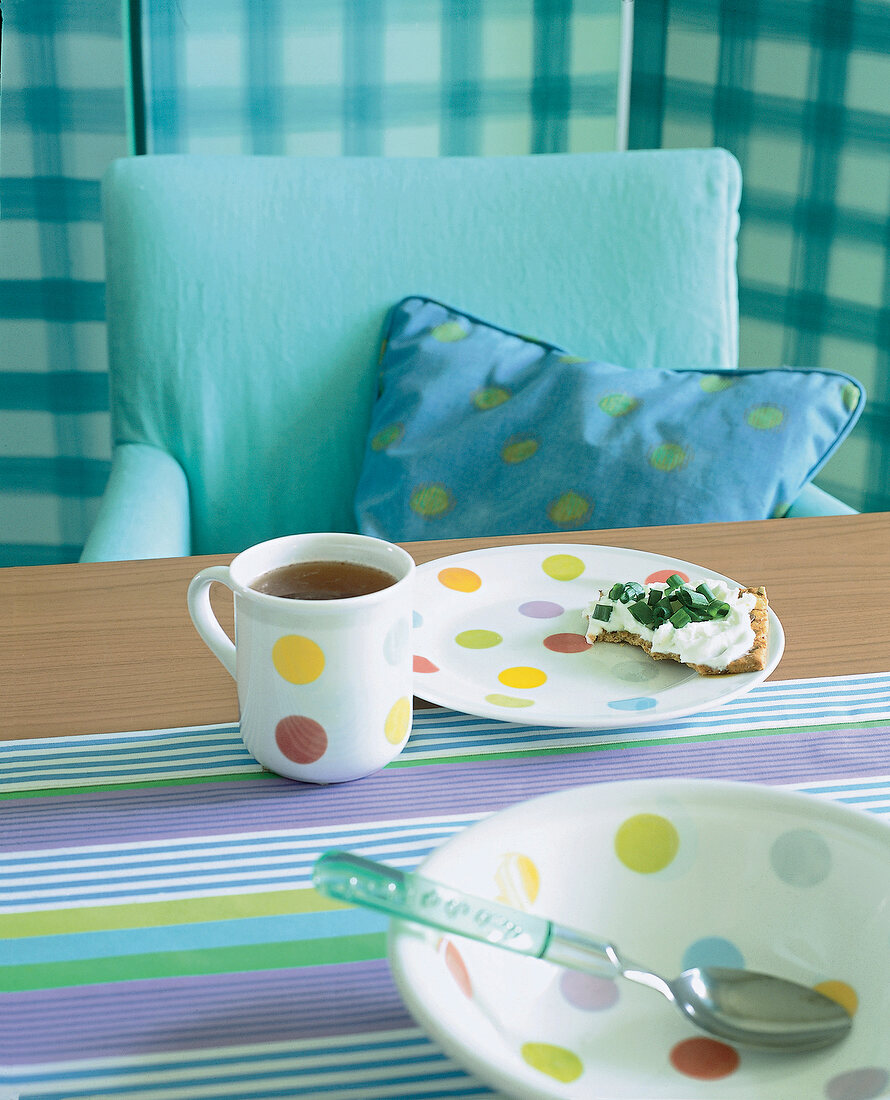 Cup and dishes with multi coloured polka dots on table