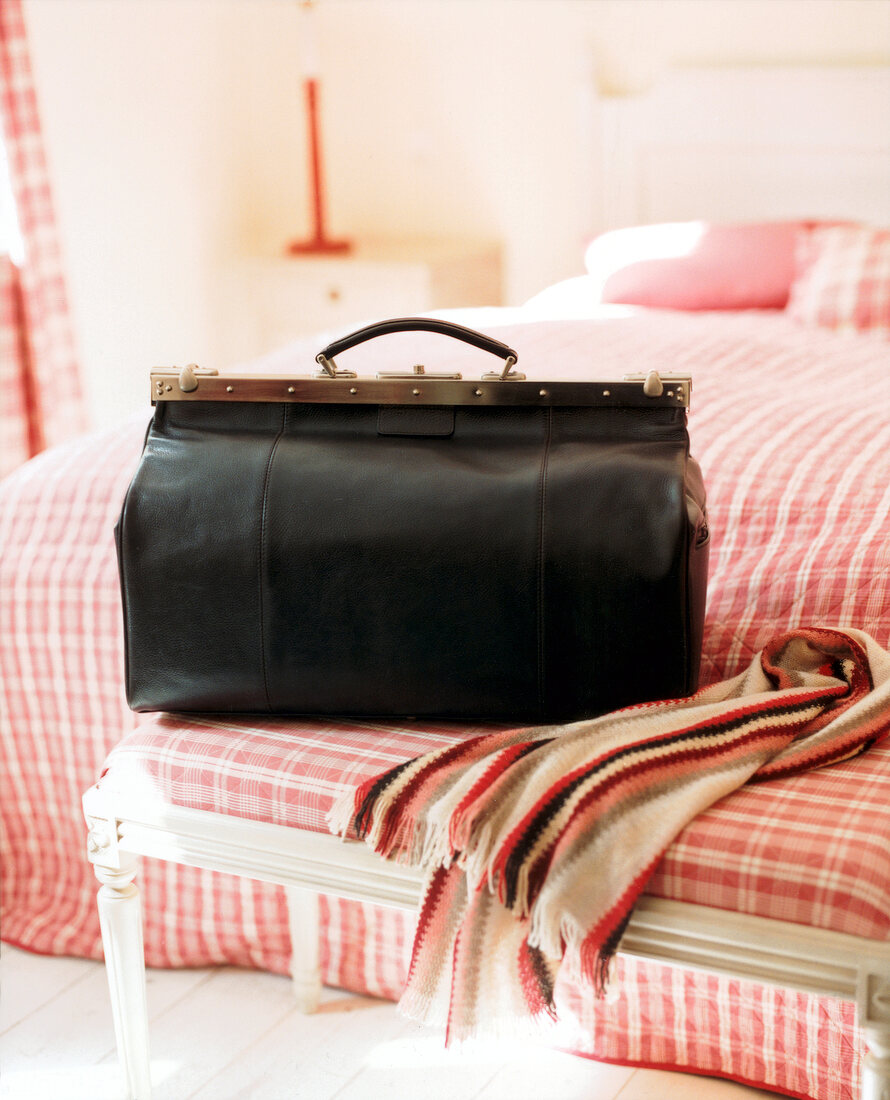 Black leather bag with metal closures on bed