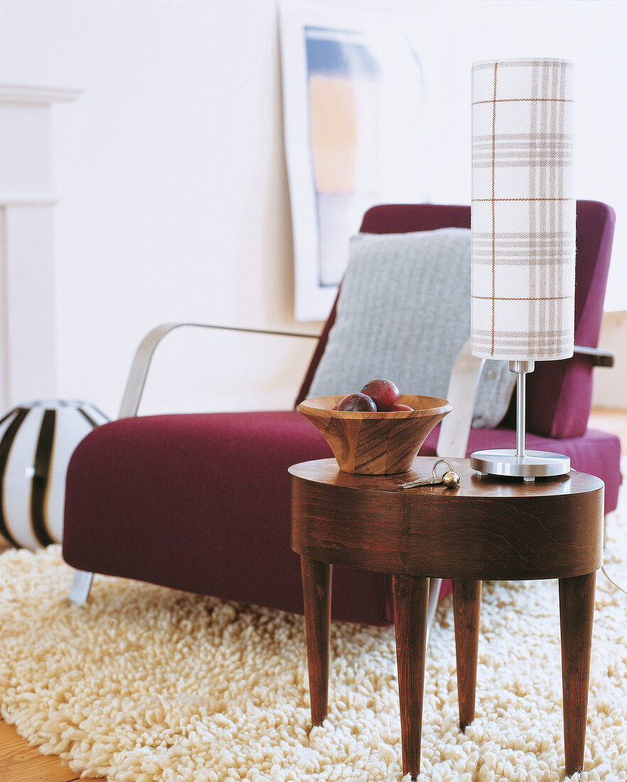 Chair with purple felt cover and oval coffee table with table lamp in front