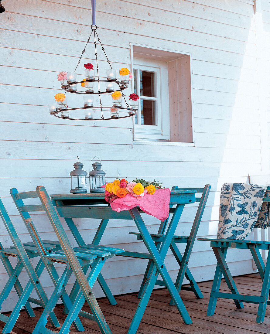 Wrought iron chandelier above blue wooden folding table and chairs