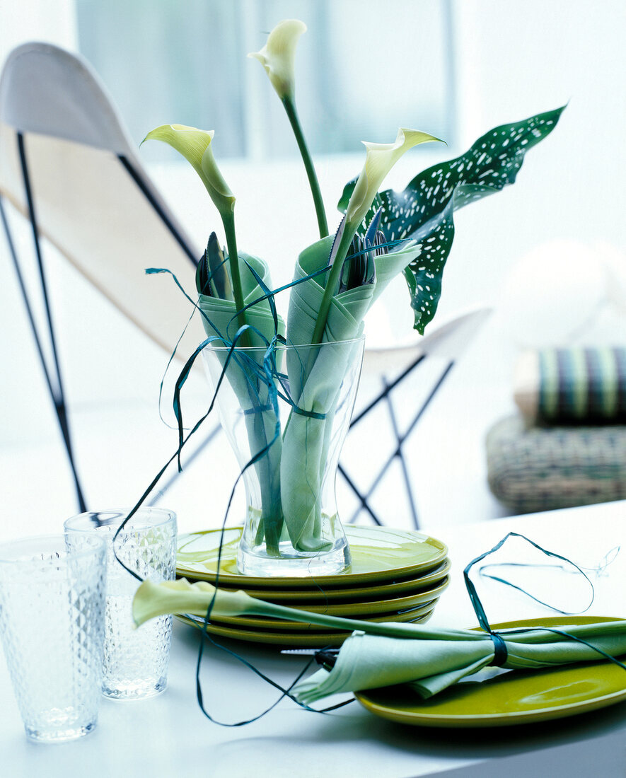 Cutlery wrapped in napkins decorated with calla in glass