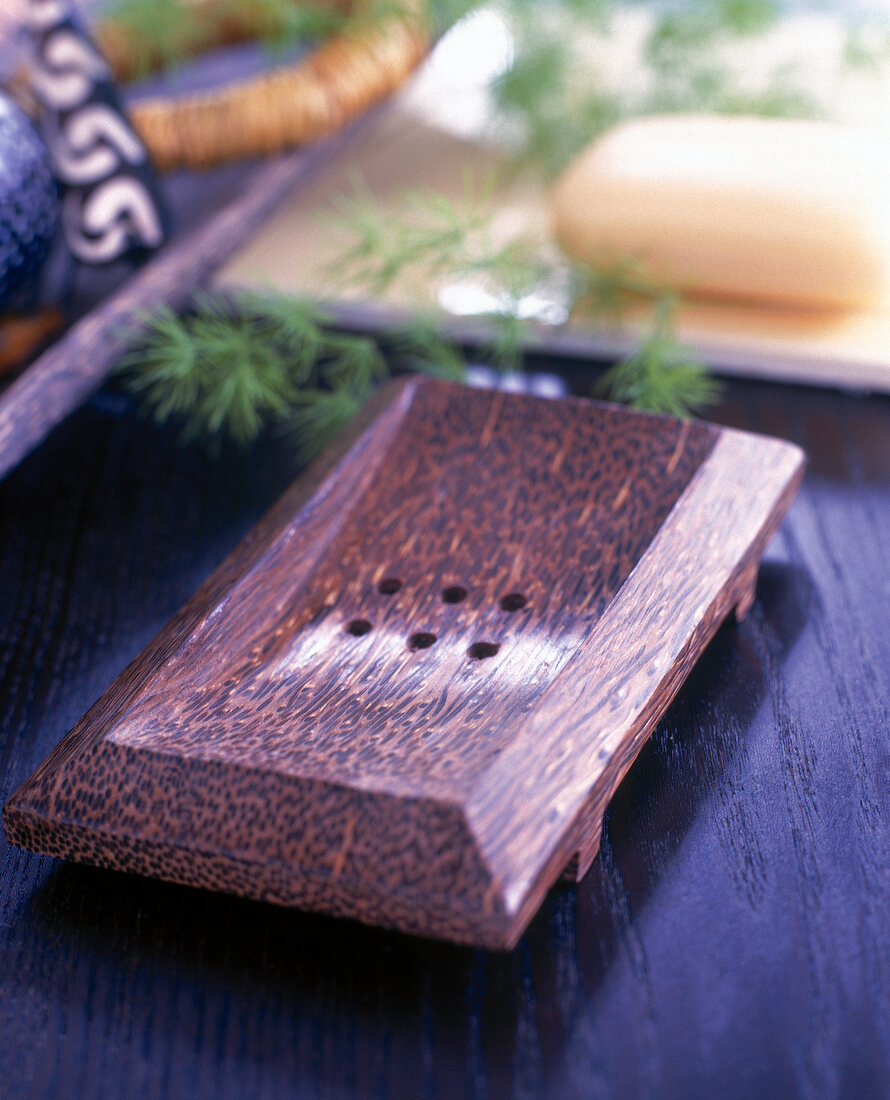 Soap dish made up of palm wood on wooden background