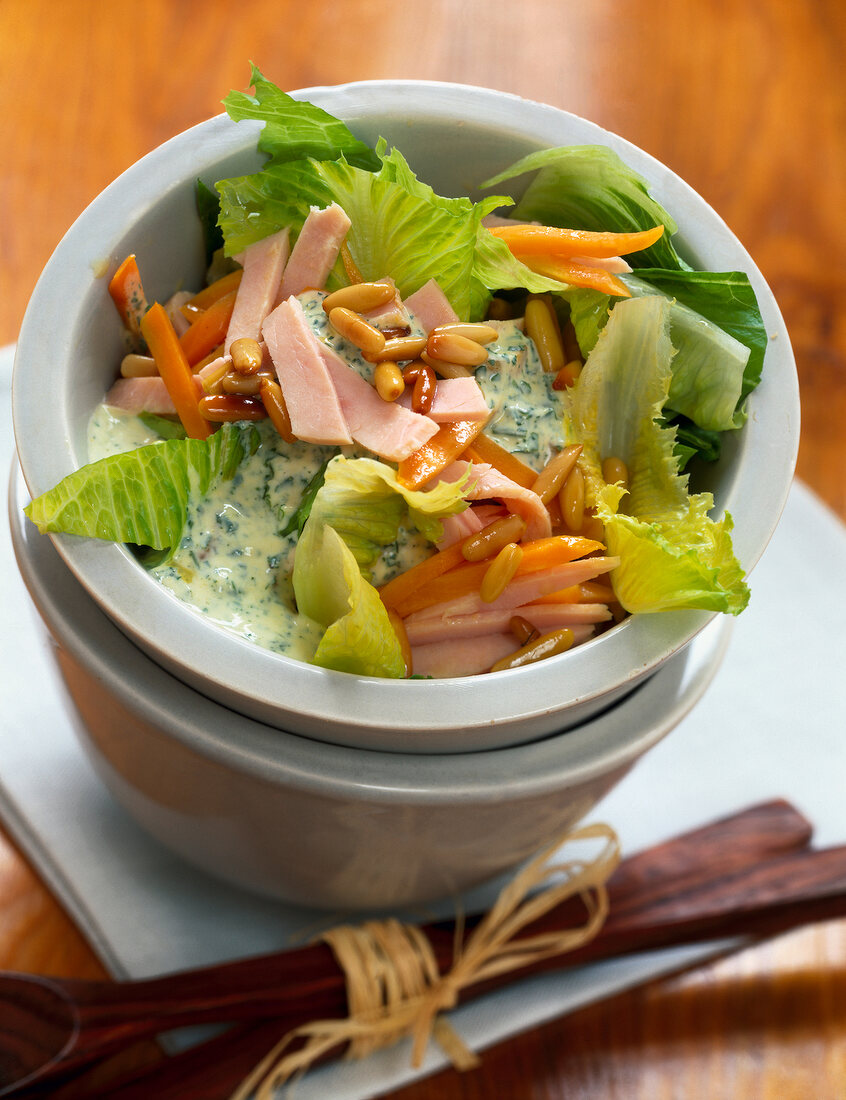 Romaine lettuce with carrots, turkey breast and pine nuts on plate