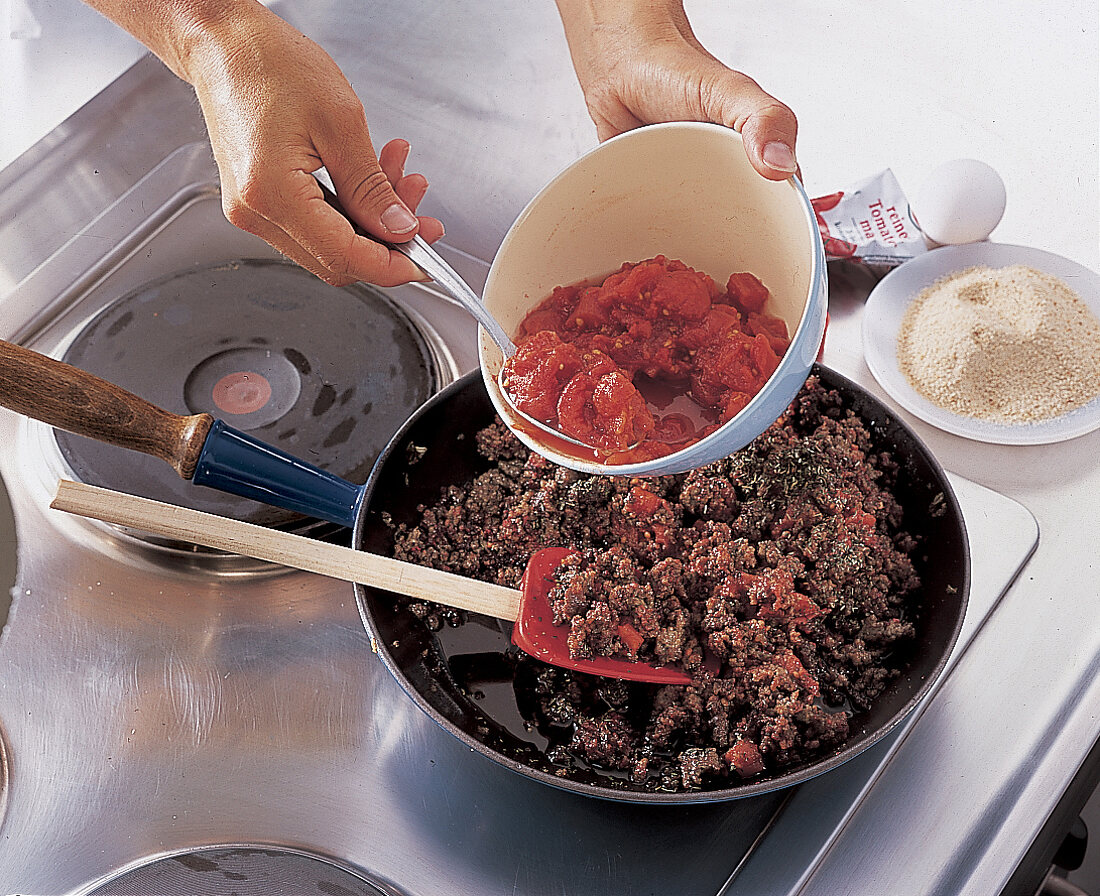 Für den Pastitsio Tomaten unter die Hacksoße geben. Nr. 3