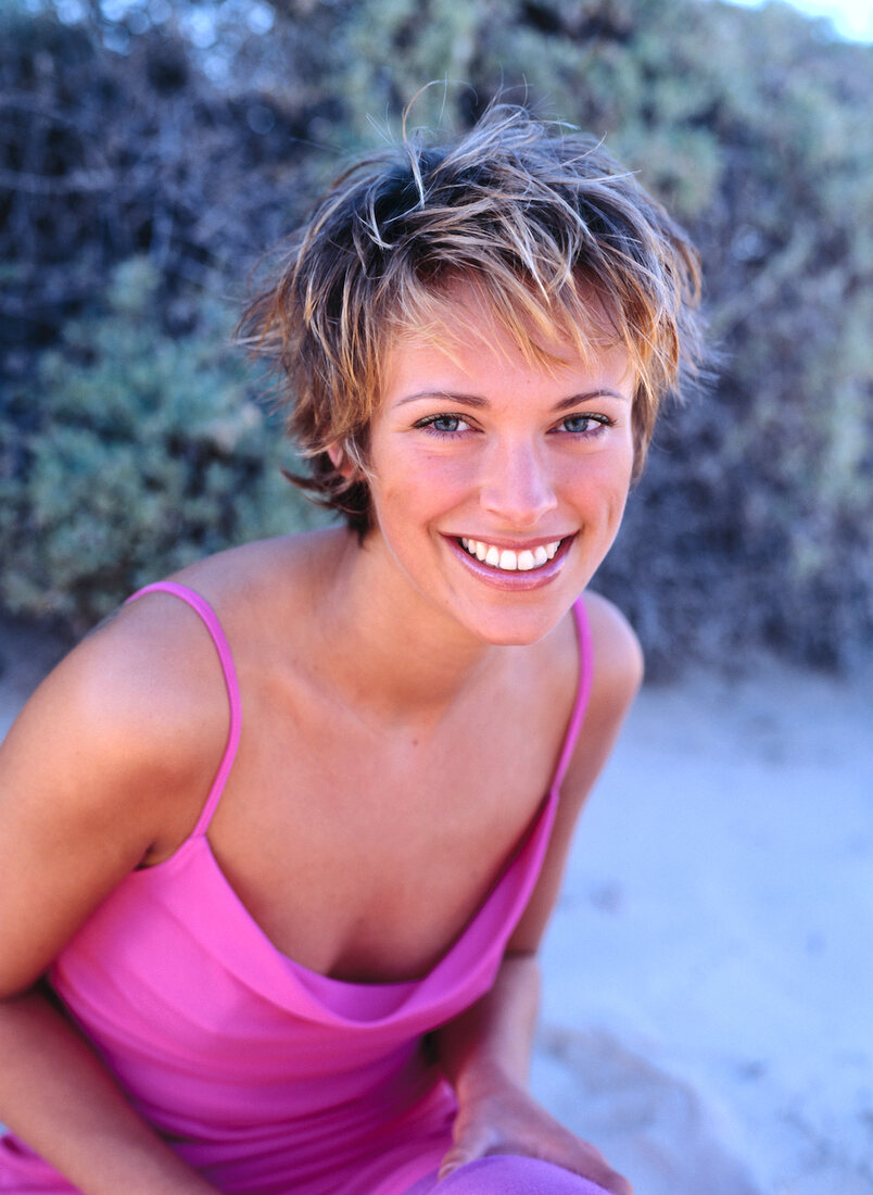 Portrait of happy woman with short hair wearing pink spaghetti straps dress, smiling