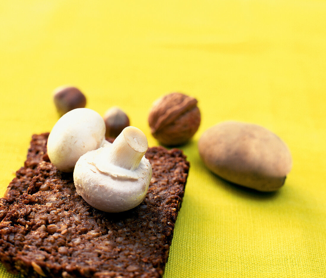 Vollkornbrot, Champignons, Nüsse, Kartoffel auf gelbem Untergrund