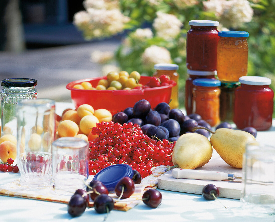 Summer fruits, jams, jellies and empty jars on table