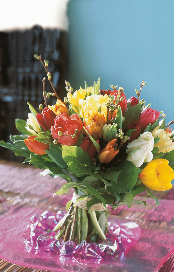 Bouquet of colourful tulips in glass bowl on table