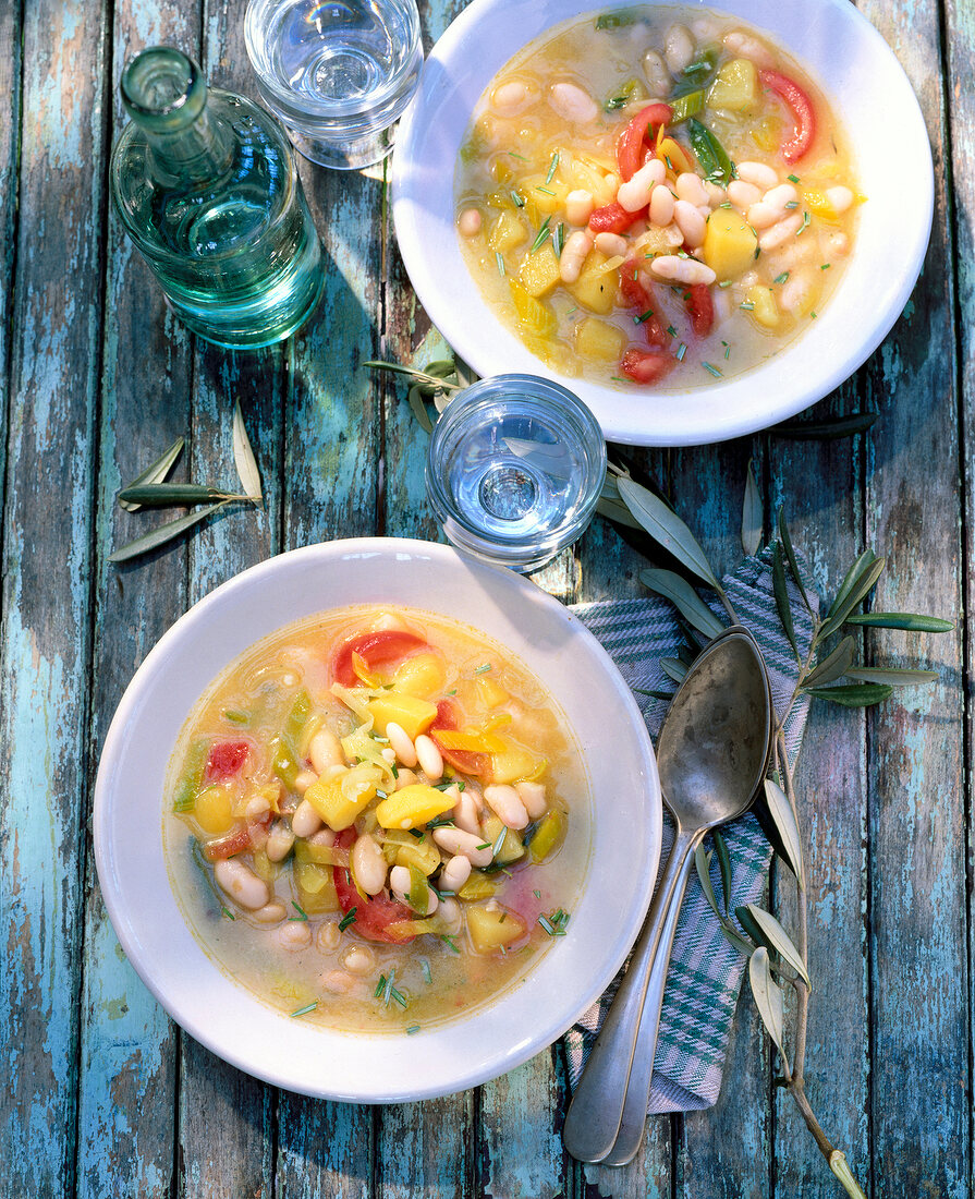 Vegetable soup with potatoes, leeks and beans on wooden surface, overhead view