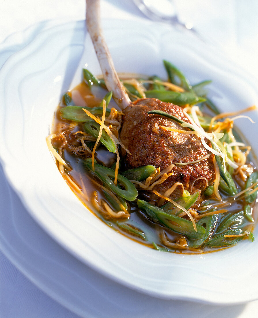 Close-up of stuffed lamb chops in tom-yam soup in white serving dish