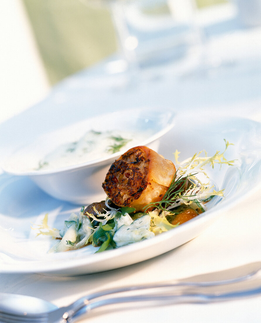 Close-up of cabbage strudel with braised cucumber salad on plate