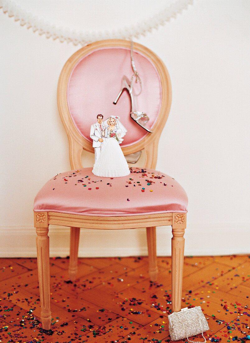 Figurine of bride and groom made of paper mache on chair