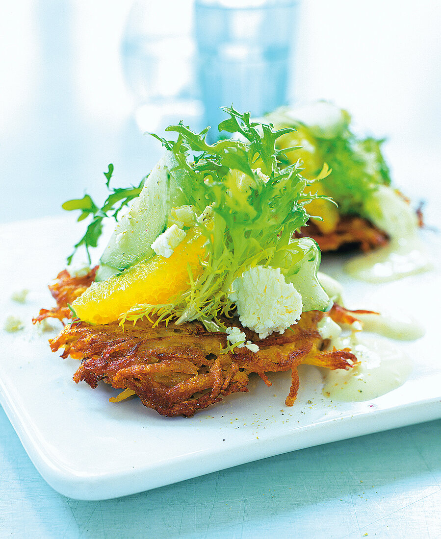 Close-up of hash brown, oranges, feta cheese and cucumber salad on square plate