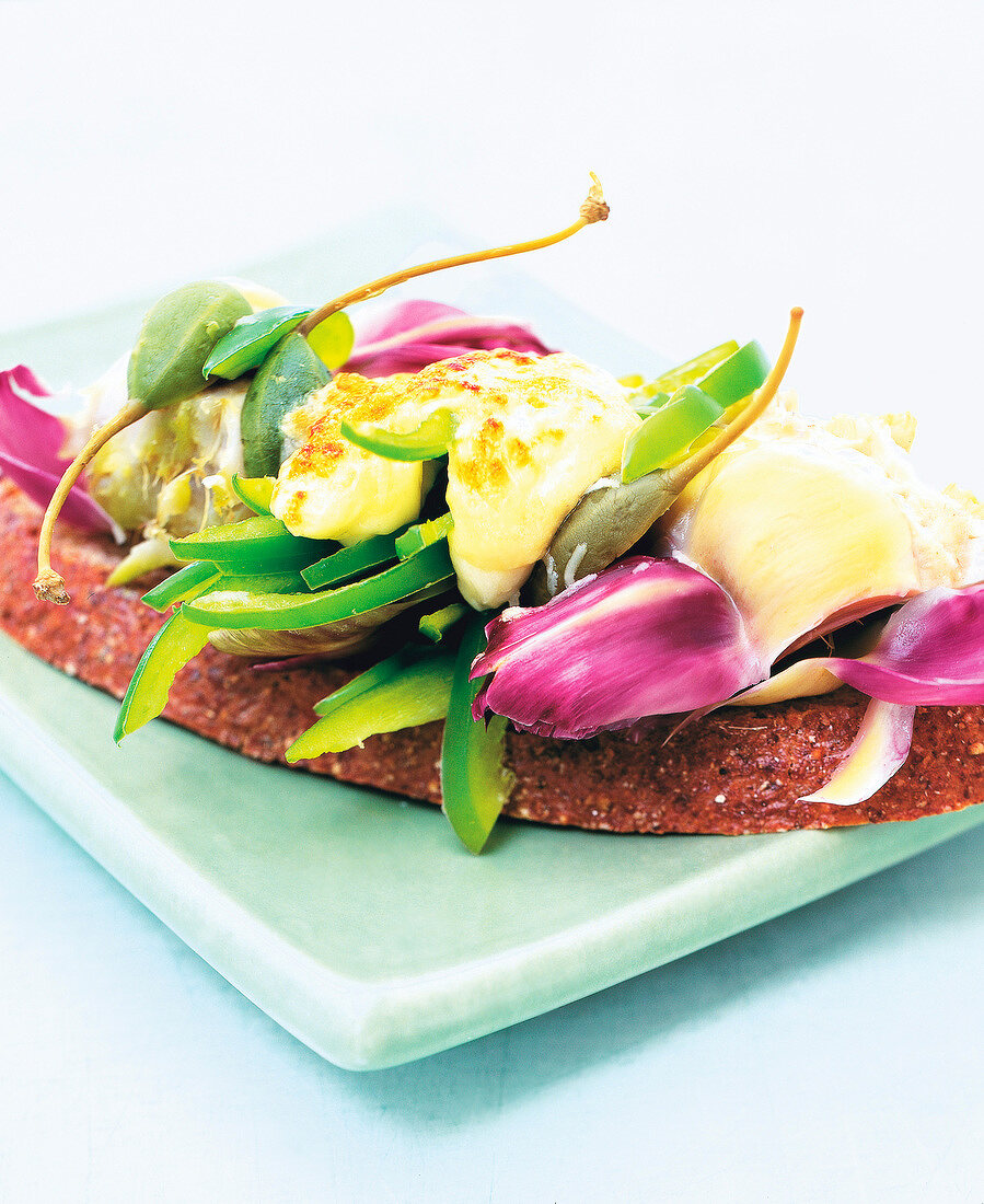 Close-up of baked green peppers and artichoke hearts on brown bread