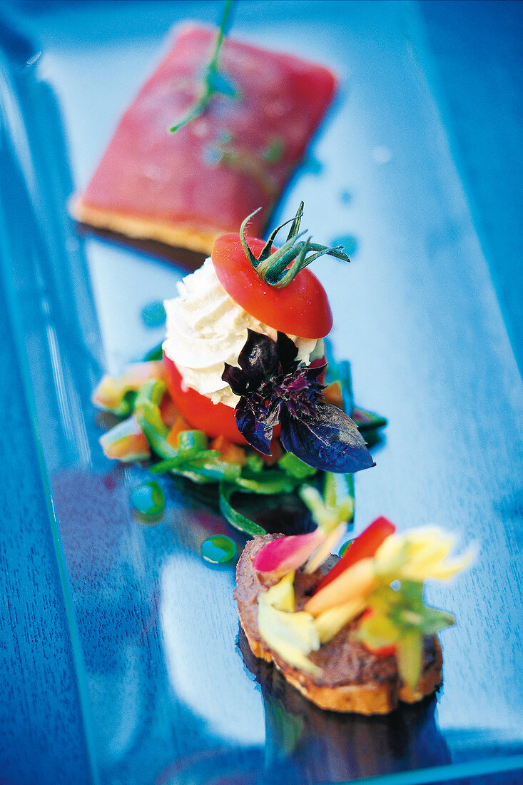 Tomato stuffed with goat cheese and half-raw grilled tuna on blue tray