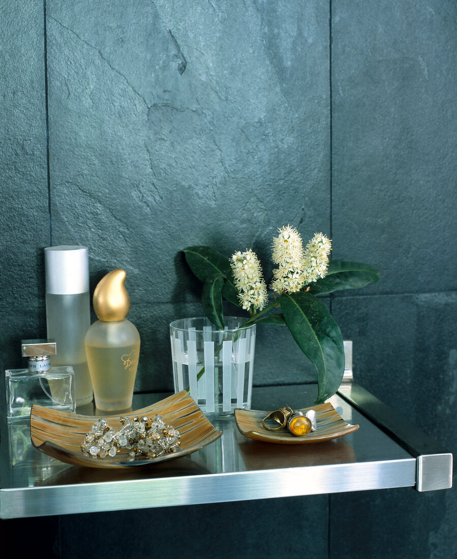 Perfume bottles, bowls of jewellery, glass with branch in bathroom