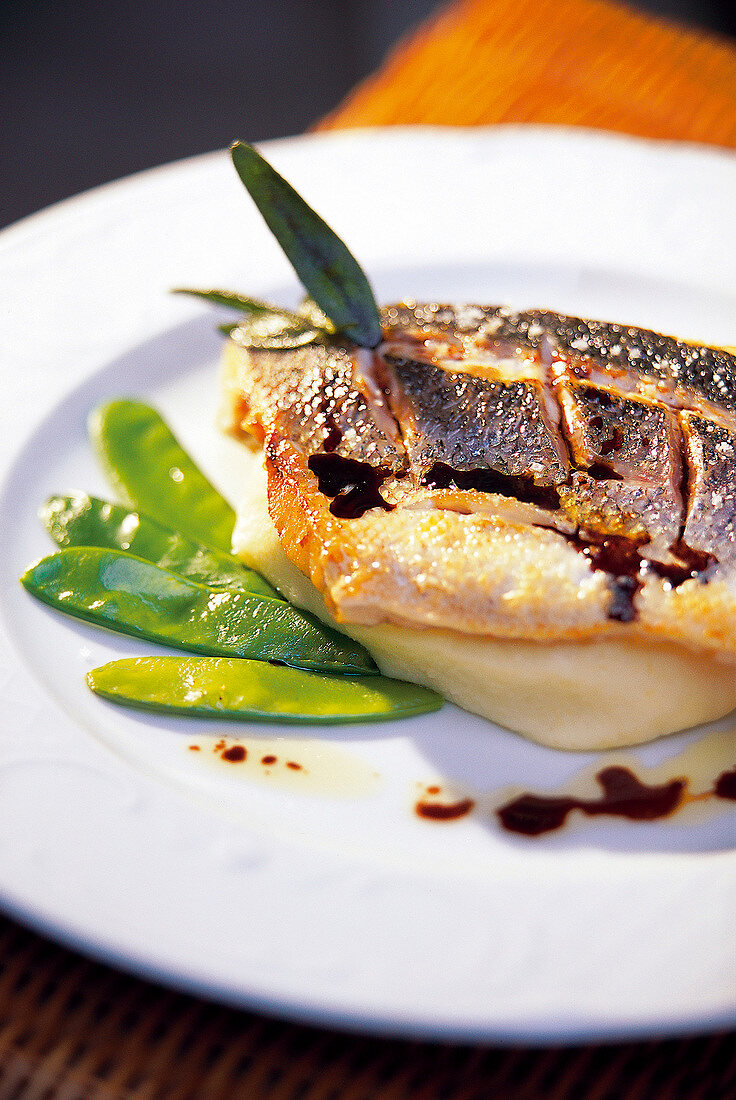 Close-up of sea bass with mashed potatoes and snow peas on plate