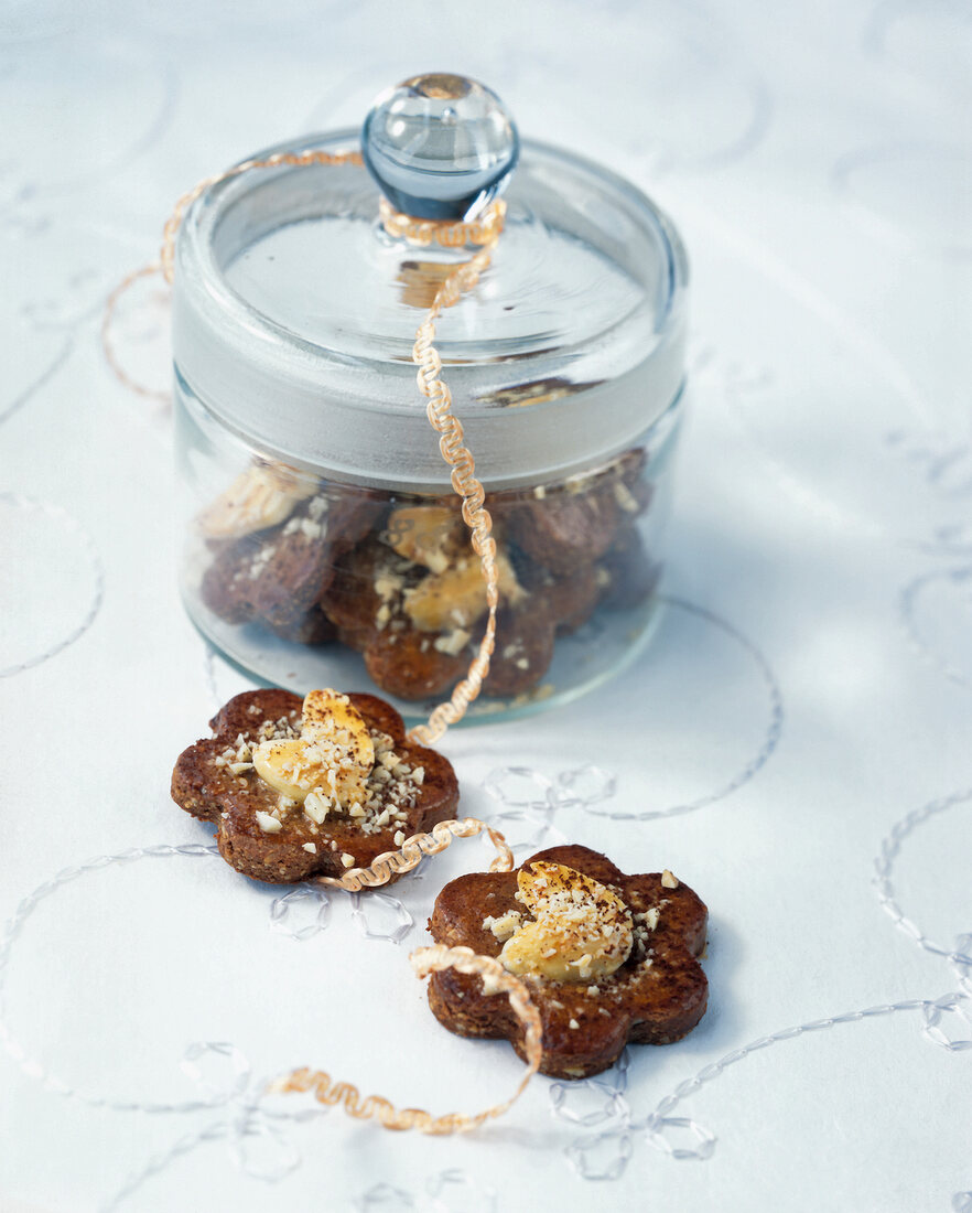 Cinnamon and almond dollar cookies in glass jar with lid on white surface
