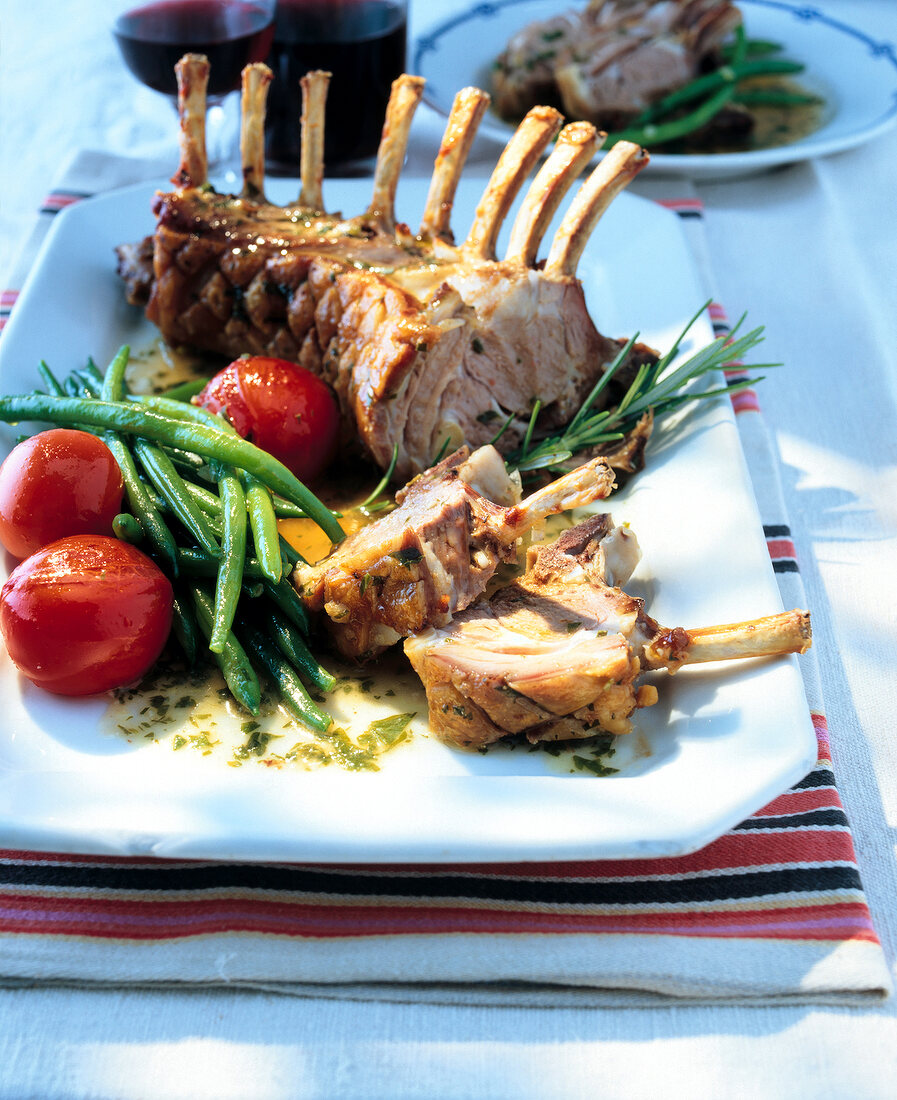 French recipe of rack of lamb with tomatoes, garlic, asparagus and thyme in serving dish