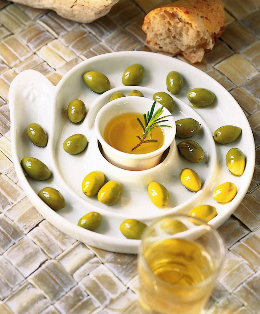 Viele grüne Oliven in einer schneckenförmigen Keramikschale