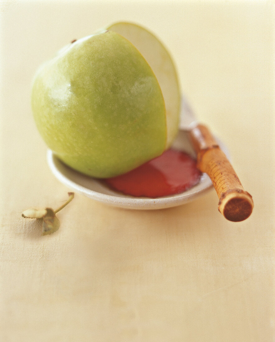 Close-up of green apple and knife on saucer