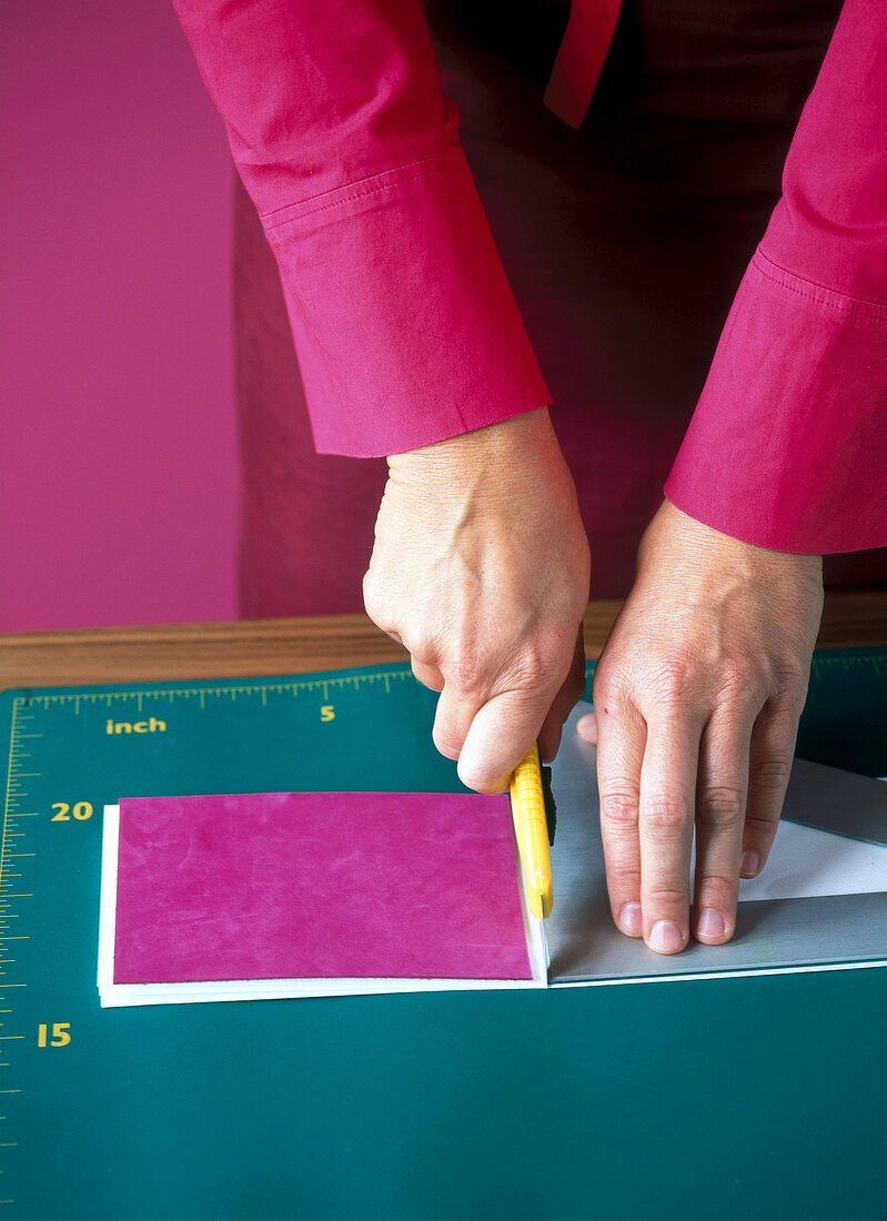 Woman cutting extra paper with cutting knife while making leporello album