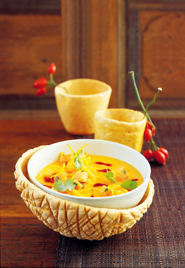 Pumpkin and orange soup with coriander croutons in bowl