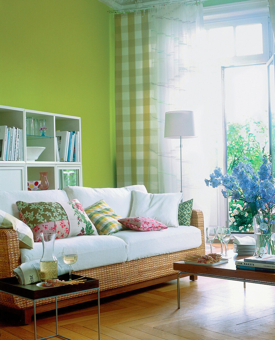 Wohnzimmer mit Couch aus Korb, grüner Wand, Parkettboden X.