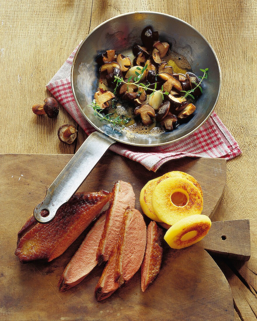 Chestnuts with sliced duck breast and caramelized ouitten on wooden chopping board
