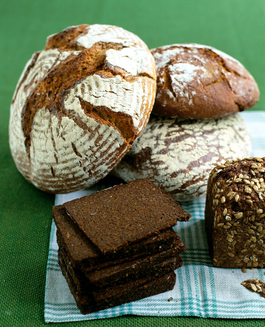 Different types of brown bread on green surface