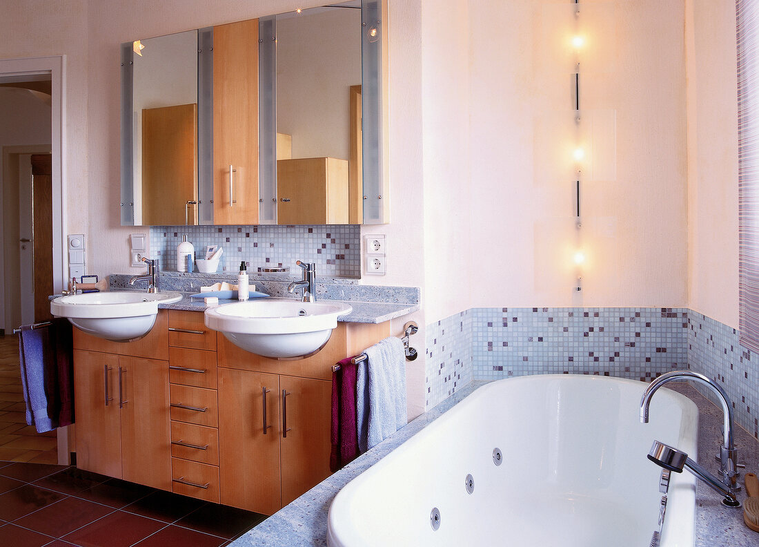 Interior of bathroom with maple and blue mosaic tiles, bathtub and sink