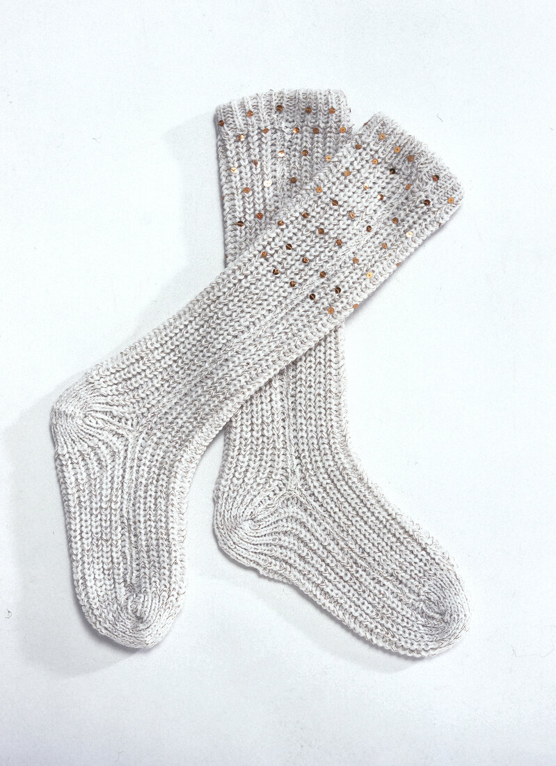 Woolen socks decorated with sequins on white background