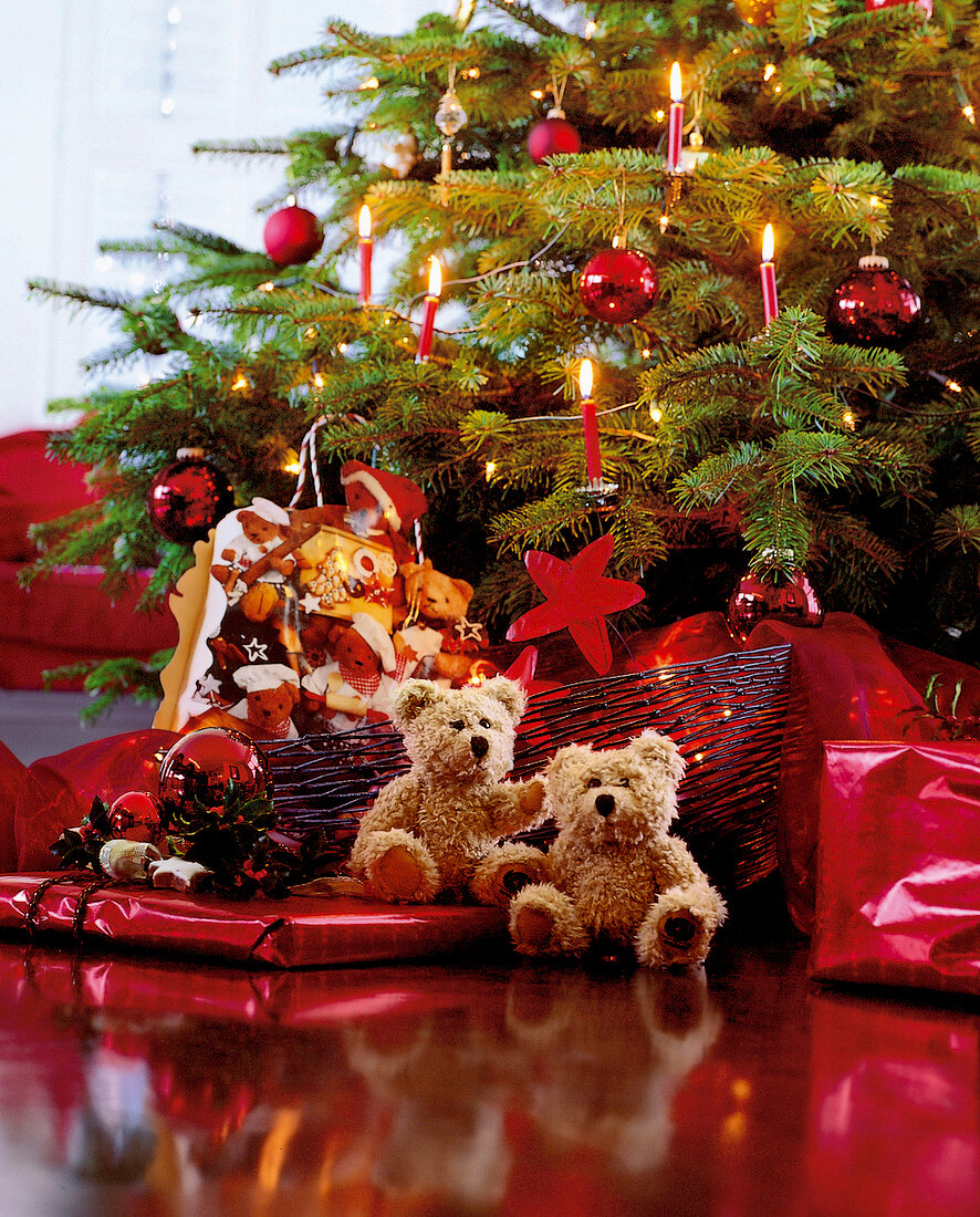 Geschenke und Teddys unter geschmückten Weihnachtsbaum