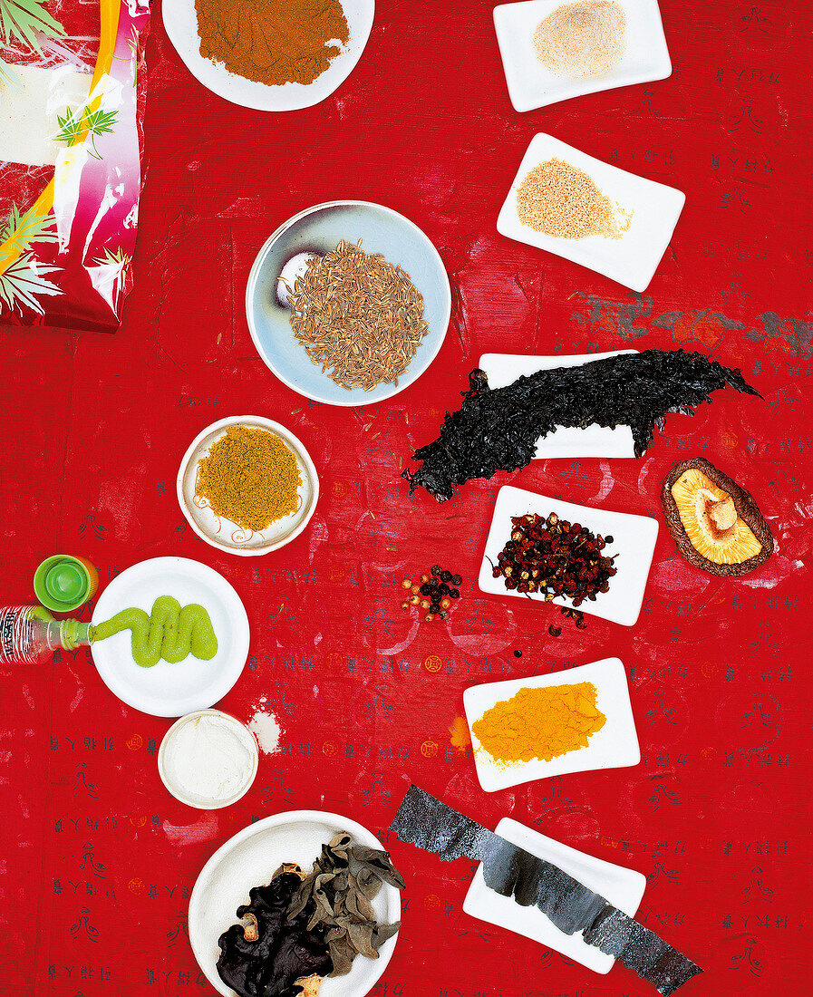 Various plates of Asian spices on red background